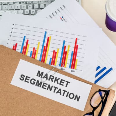 Top view of a folder labelled "MARKET SEGMENTATION" on a laptop with charts on it in the office